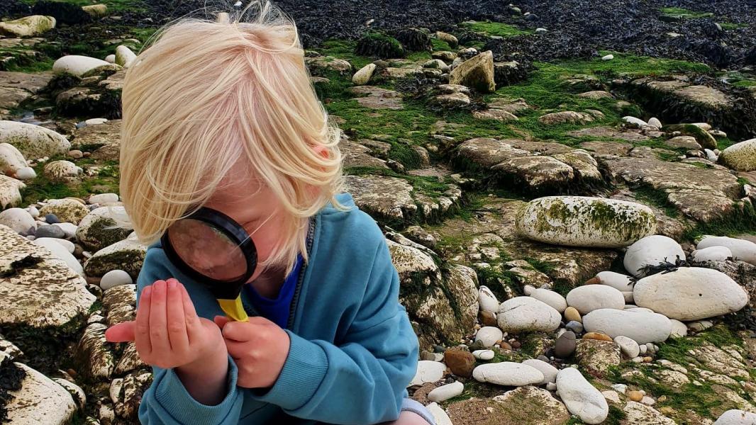 A young boy looking through a microscope down at the beach at Sewerby.