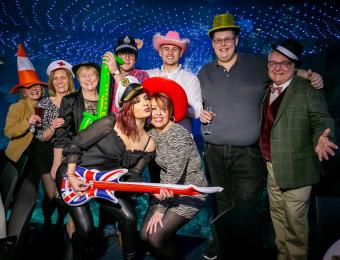 A group of people posing with props at a Christmas Party event in The Deep.