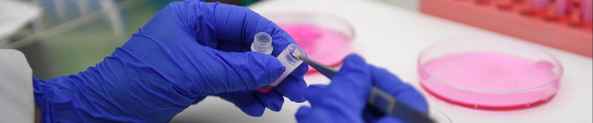 A woman wearing blue gloves in a lab sampling.