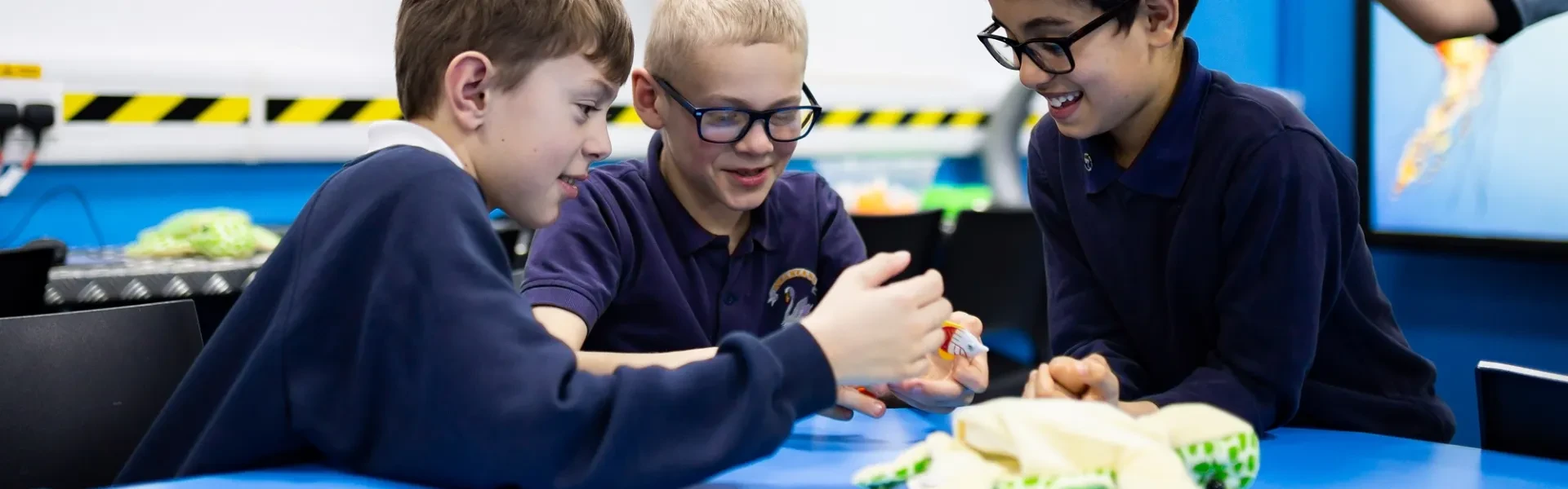 3 young school children smiling and engaging with the educational resources in The Deep's classroom